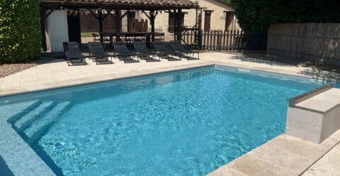 Family-friendly pool area with outdoor dining space in rural France.